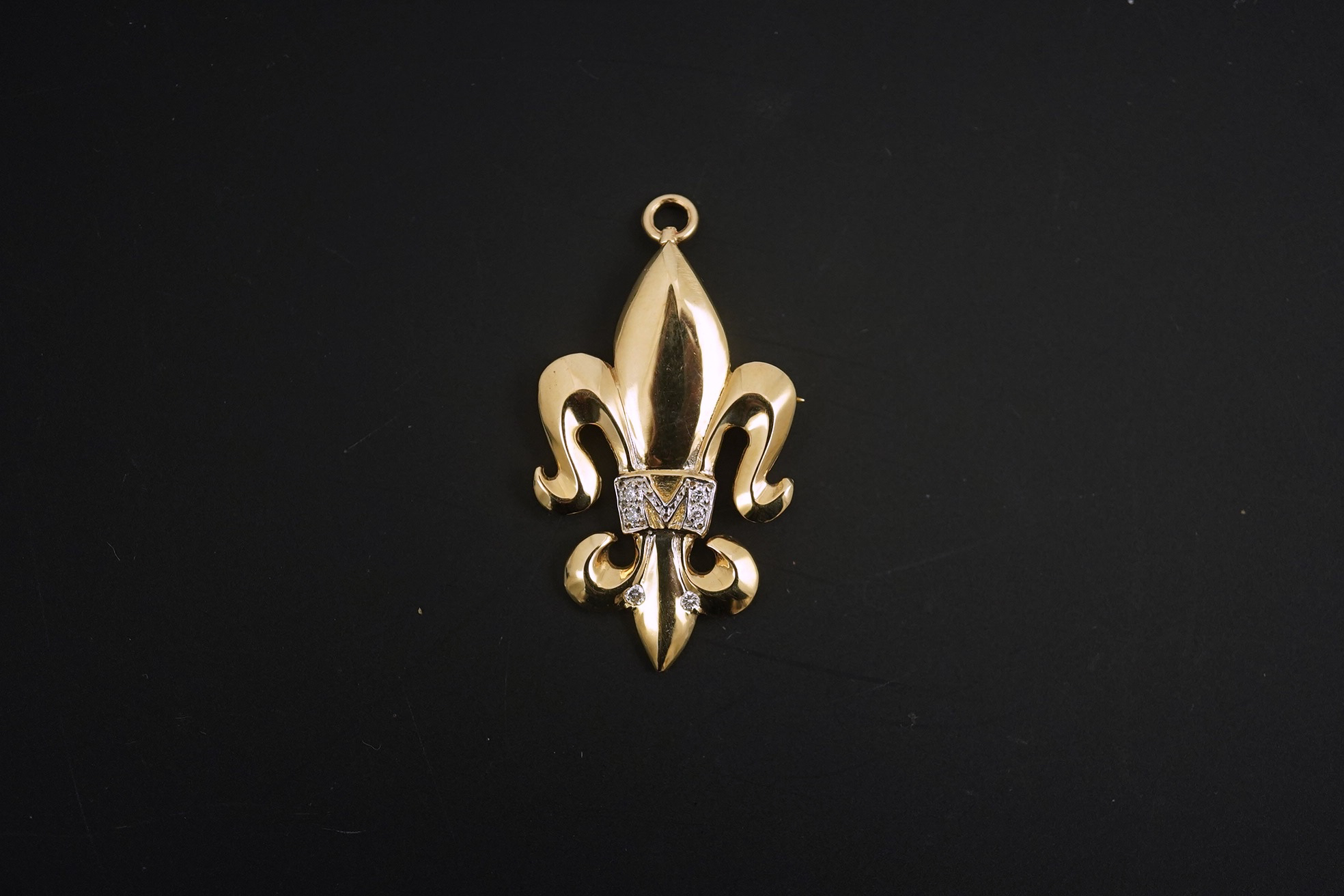 A modern 14k gold and diamond chip cluster set fleur de lys pendant